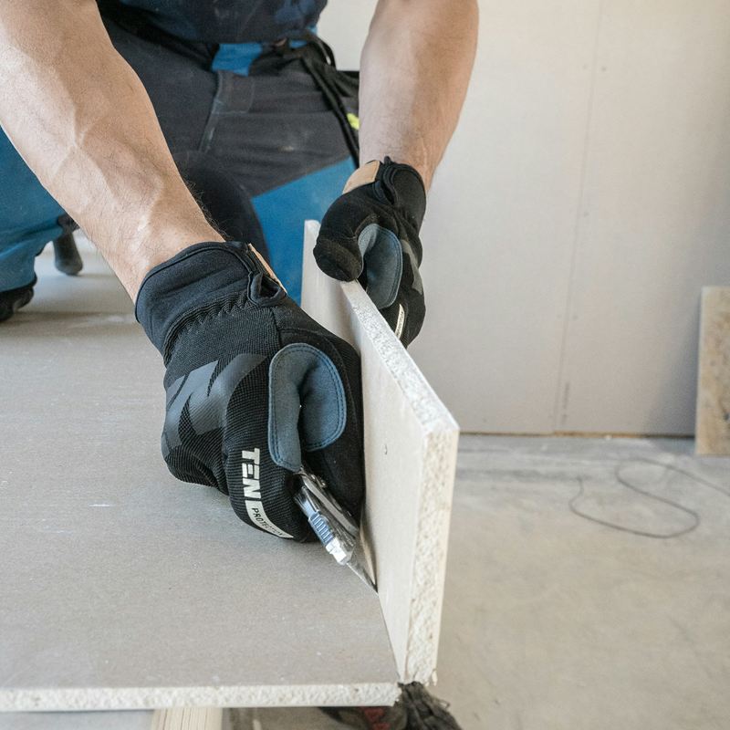 Un cartongessista che taglia un pannello di cartongesso