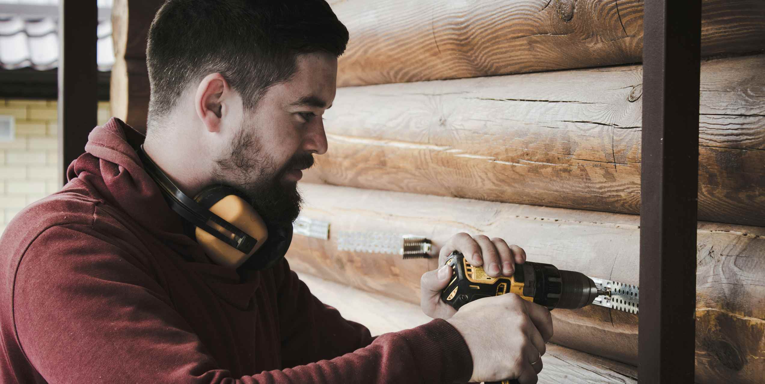 Un operaio che fissa delle viti su dei tronchi